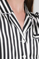 Close-up of 100% Mulberry Silk black and white striped long sleeve pajama top with white buttons and pocket detailing