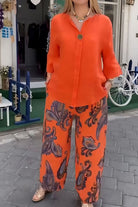 woman wearing vibrant fusion two-piece set with orange top and patterned wide-leg pants