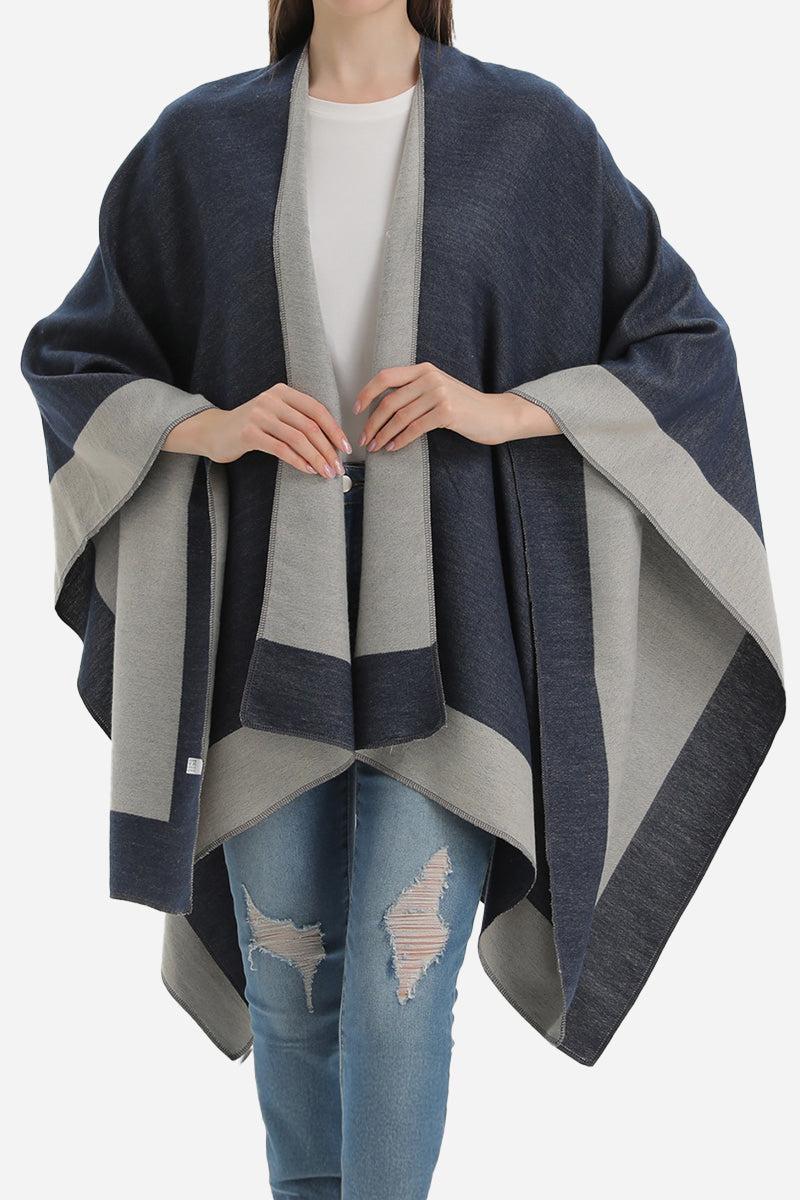 Elegant knitted two-tone poncho draped over model with casual outfit