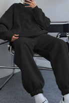 Black comfy chic tracksuit with relaxed fit, long sleeves, and elastic cuffs, styled for casual and loungewear.