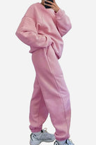 Woman wearing pink comfy chic tracksuit with relaxed fit and cozy fabric paired with white sneakers