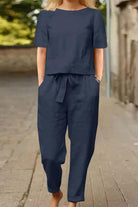 Woman wearing navy blue cotton-linen blend monochrome two-piece set with short sleeves and relaxed fit pants walking outdoors
