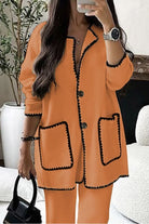 Orange contrast-trim knit cardigan with button front and pockets, styled with matching pants