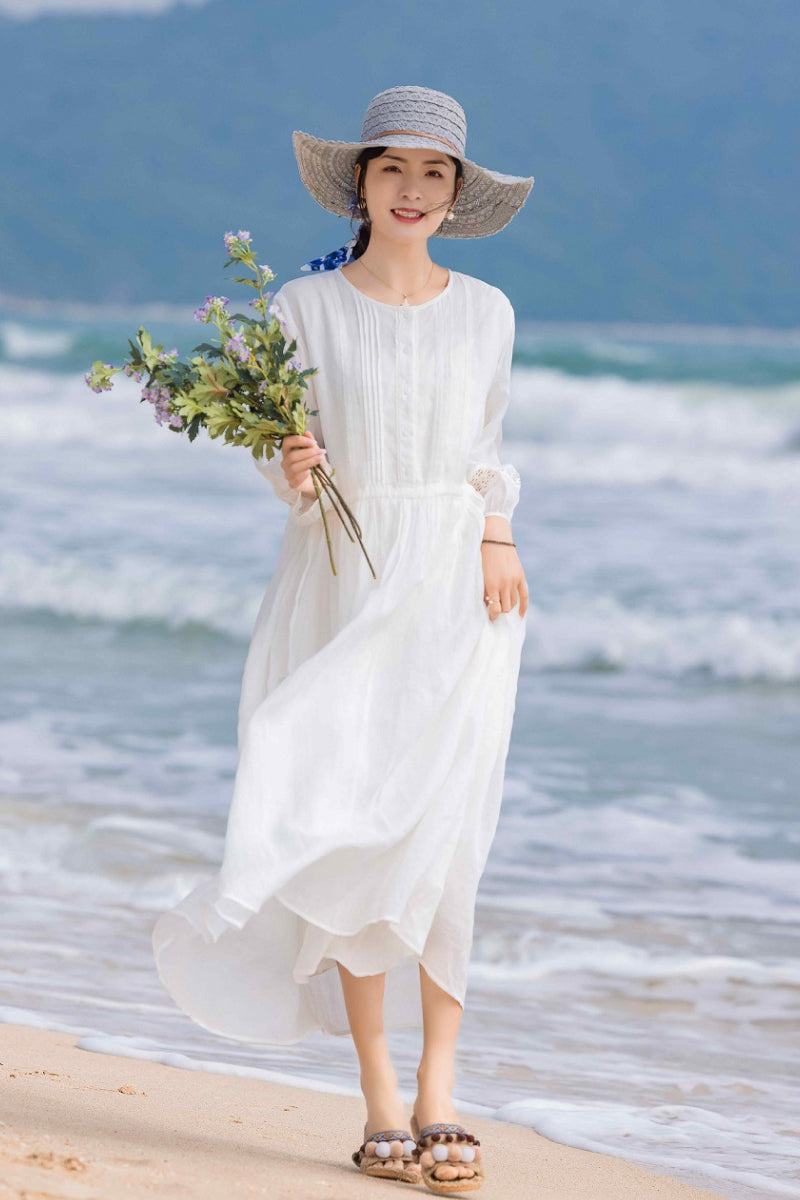 woman wearing 100 linen coastal shift white dress on beach holding flowers