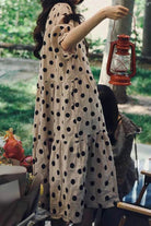 Cottage Garden 100 Linen Dress beige with black polka dots tiered relaxed fit holding lantern in garden setting