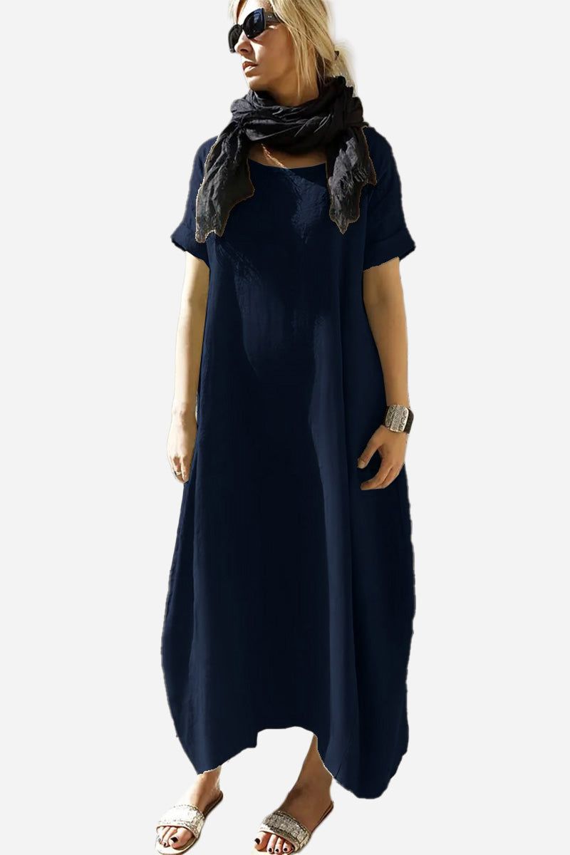 Woman wearing navy Breeze Cocoon Dress with rolled sleeves and deep pockets, styled with scarf and sandals