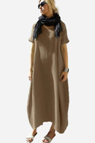 Woman wearing a relaxed brown Breeze Cocoon Dress with rolled sleeves, deep side pockets, and a black scarf.