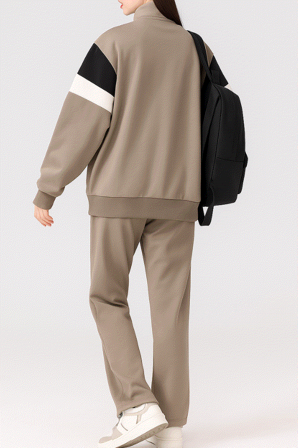 Comfort in Motion lightweight athleisure tracksuit set in taupe with black and white sleeve detail, worn with white sneakers and black backpack.