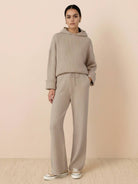 woman wearing beige waffle-knit two-piece hoodie and pants set standing against beige background