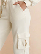 Close-up of cream-colored cotton waffle knit pants with adjustable drawstring and cargo pockets