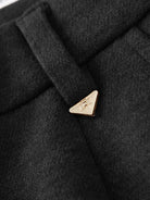 Close-up of black thermal wool blend trousers with gold triangular button and textured fabric detail