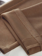 Close-up of brown thermal wool blend trousers fabric with folded cuffs and stitching detail