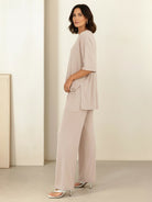 Woman wearing oversized long-line loungewear set with pullover and wide-leg pants in soft knit fabric