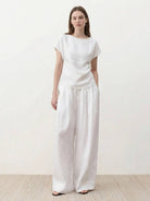 White Tencel-linen pleated wide-leg pants with structured waist and floor-skimming silhouette