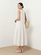 Woman wearing a cotton-linen summer midi dress with a tiered skirt and relaxed drop-waist silhouette in natural fabric