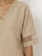 Mature woman wearing a lightweight linen top with V-neck and button detail in a relaxed boxy fit