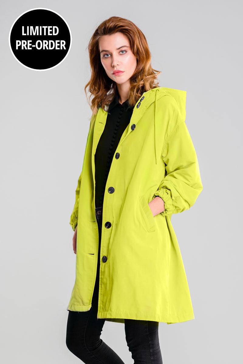 Woman wearing lime green water-resistant windbreaker jacket with hood and button closure