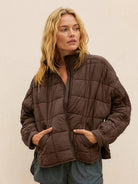 Woman wearing a brown lightweight puffer travel jacket with zip front and pockets