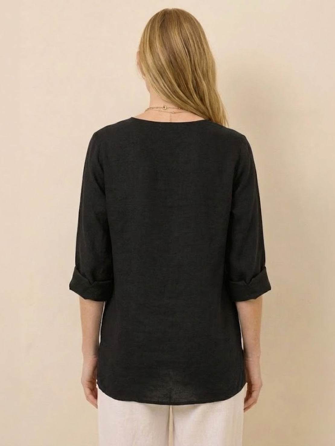Back view of a woman wearing a black Pure Linen Age-Defying Button Detail Shirt with rolled-up sleeves.