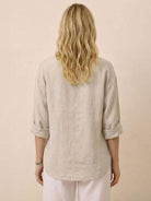 Back view of woman wearing beige pure linen age-defying button detail shirt with rolled sleeves