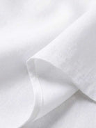 Close-up of white breathable fabric texture from asymmetrical two-piece trouser set