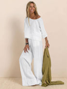 woman wearing white short-sleeved pullover and wide trouser matching set holding olive green fabric