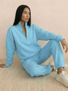 Woman wearing a cotton-blended two-piece tracksuit with high collar and deep zipper, showcasing casual comfort and style.