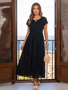 Woman wearing capped-sleeve voluminous pleated midi dress with flowing skirt and pockets