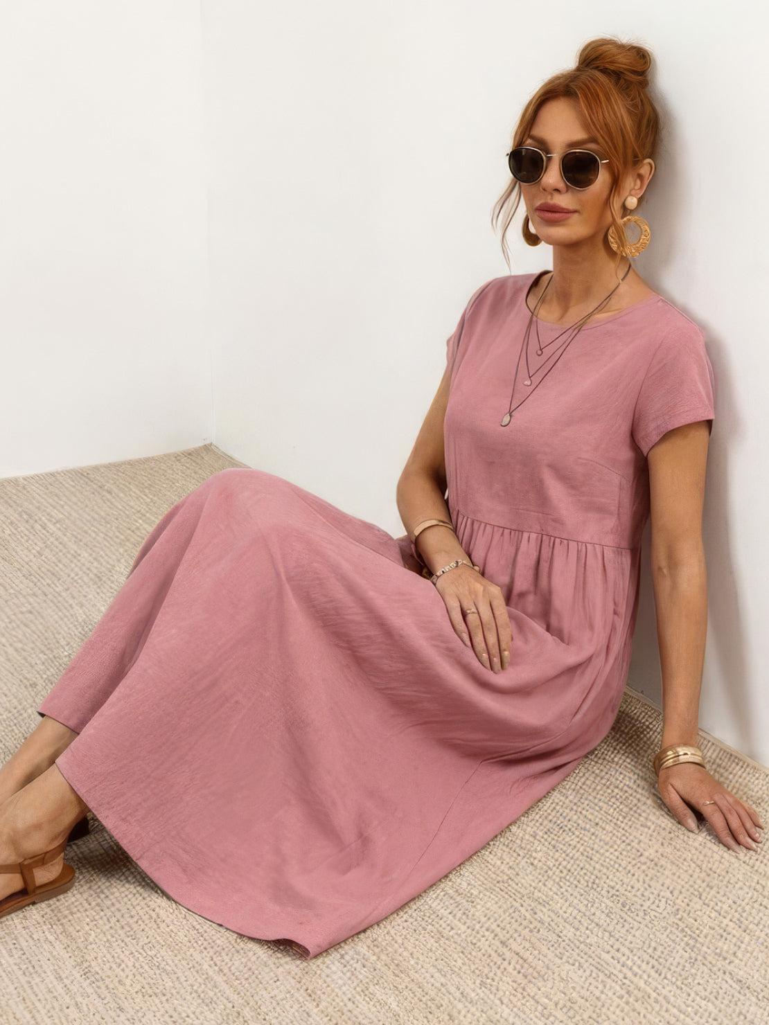 Woman wearing a capped-sleeve voluminous pleated midi dress with pockets and flowing skirt