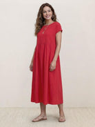 Woman wearing capped-sleeve voluminous pleated midi dress with flowing silhouette and flat stomach drape