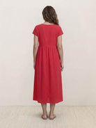 Woman wearing capped-sleeve voluminous pleated midi dress with flowing skirt and pockets