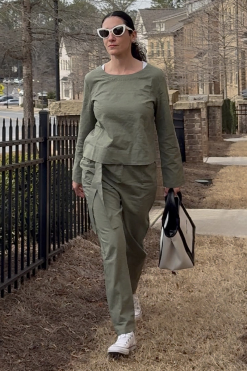 Woman wearing relaxed cotton-linen monochrome capsule outfit with longline top and wide-leg pants walking outdoors carrying a tote bag