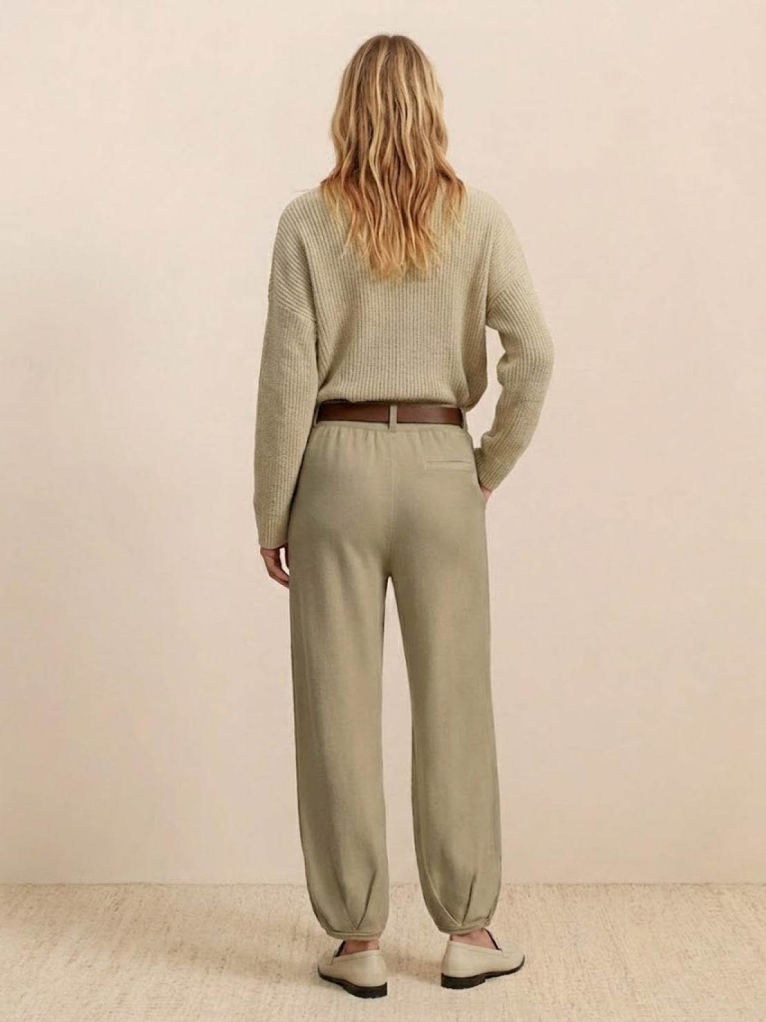Woman wearing European minimalism relaxed sweater top and khaki trousers set, back view