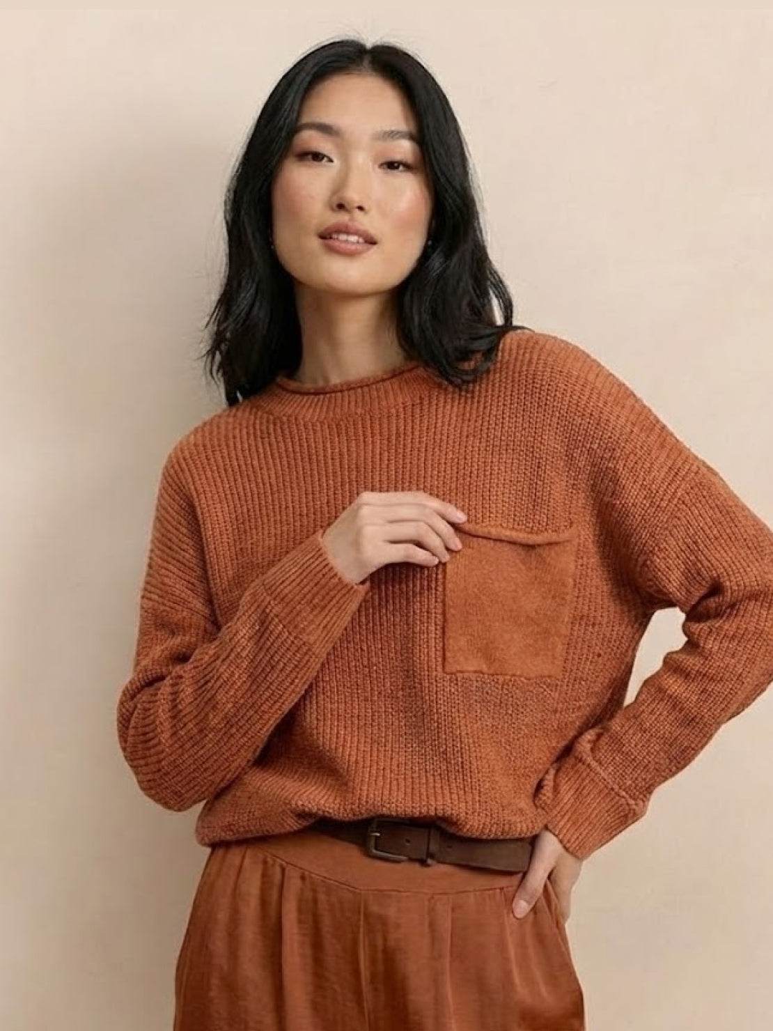 Woman wearing a rust-colored relaxed knit sweater top with pocket and matching trousers embodying European minimalism style