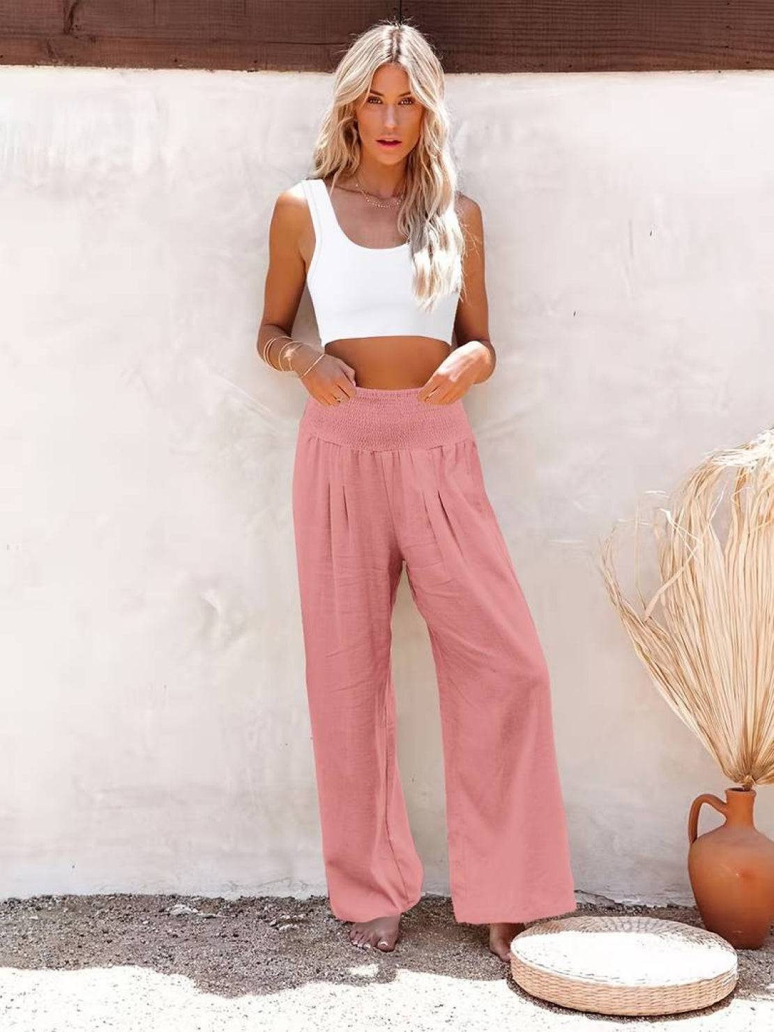 Woman wearing pink high-waist cotton linen palazzo pants with a white crop top standing outdoors