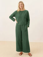 Woman wearing loose solid color two-piece green set with long sleeves and wide-leg pants