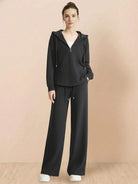 Woman wearing black Lyocell-Blend Hooded Set with wide-leg pants and hooded top against beige background