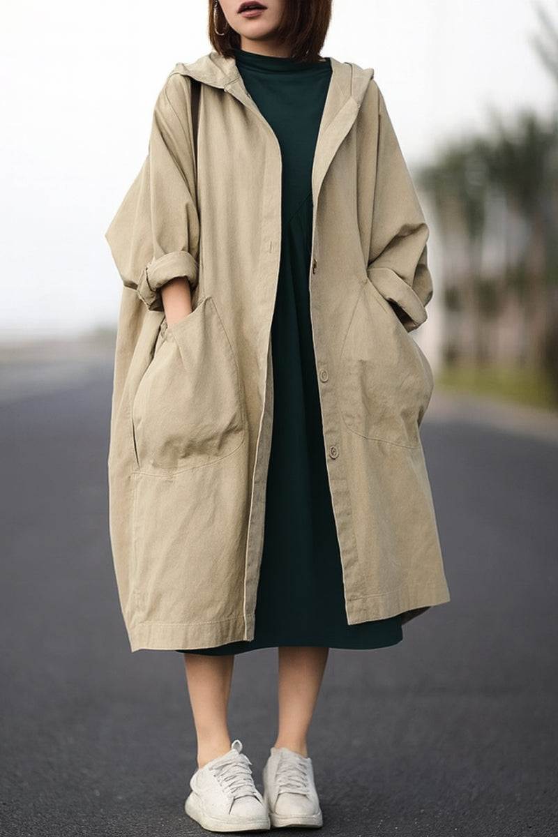 One-size oversized Heritage Windbreaker jacket in beige with attached hood and large front pockets, worn over a dark dress.