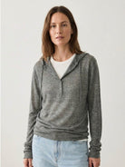 Organic linen Henley top with fine knit, relaxed fit, 3-button placket, long sleeves, and side slits in neutral heathered tones.