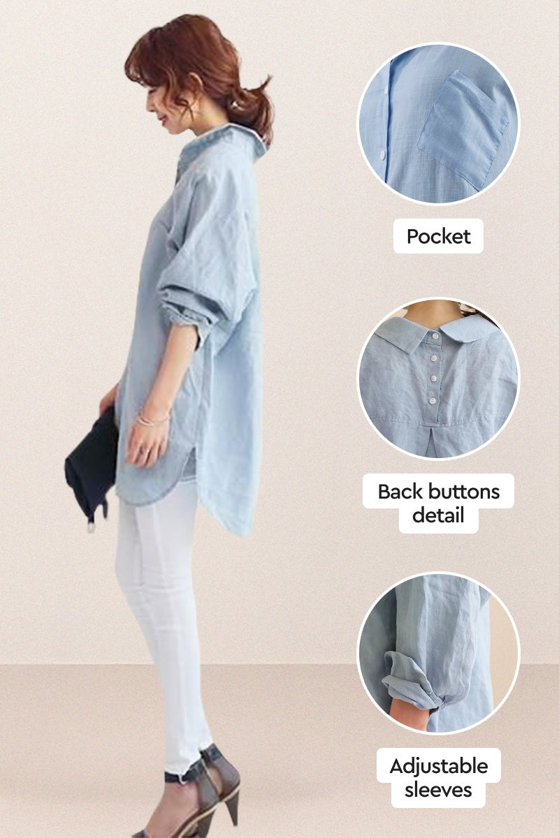 Light blue oversized linen shirt with back buttons, adjustable sleeves, and front pocket, styled on model with white pants and heels.