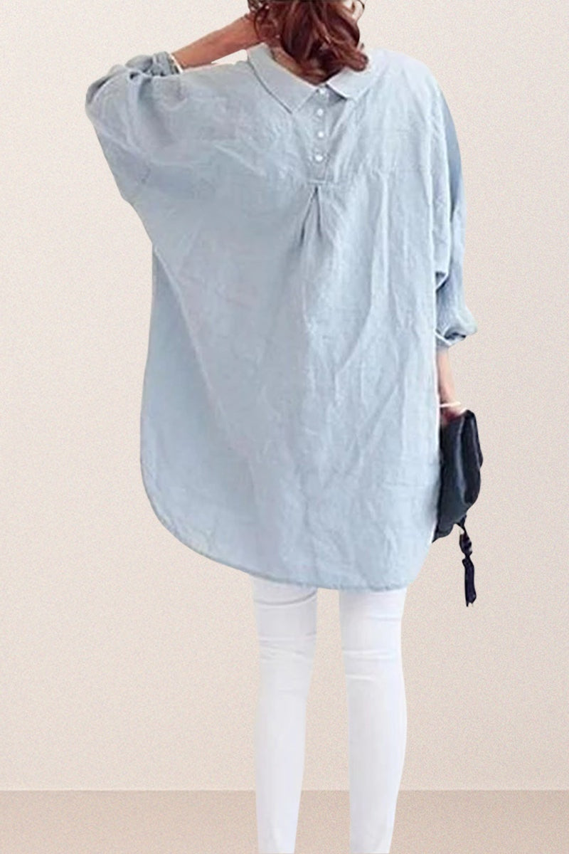 Back view of oversized linen shirt in light blue with loose sleeves and gathered back detail worn over white pants