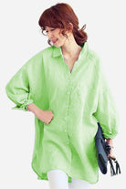 Oversized linen shirt in light green with relaxed fit and button-down front worn by a woman