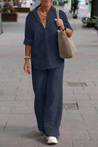 Woman wearing oversized 100% cotton navy blue shirt and wide-leg pants co-ord set walking outdoors with beige crochet bag and white shoes