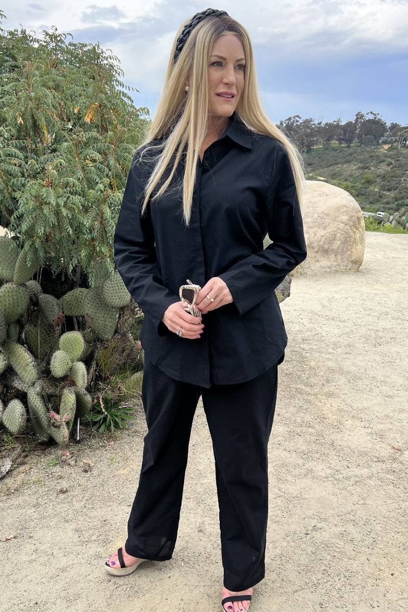 Woman wearing oversized 100% cotton black shirt and wide-leg pants co-ord set outdoors