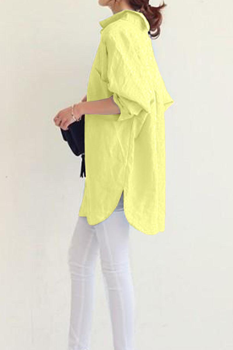 Side view of a woman wearing a yellow oversized linen shirt with long sleeves and a collared neck paired with white pants
