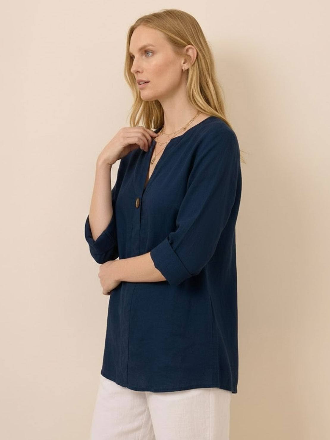 woman wearing navy blue pure linen age-defying button detail shirt with three-quarter sleeves and white pants