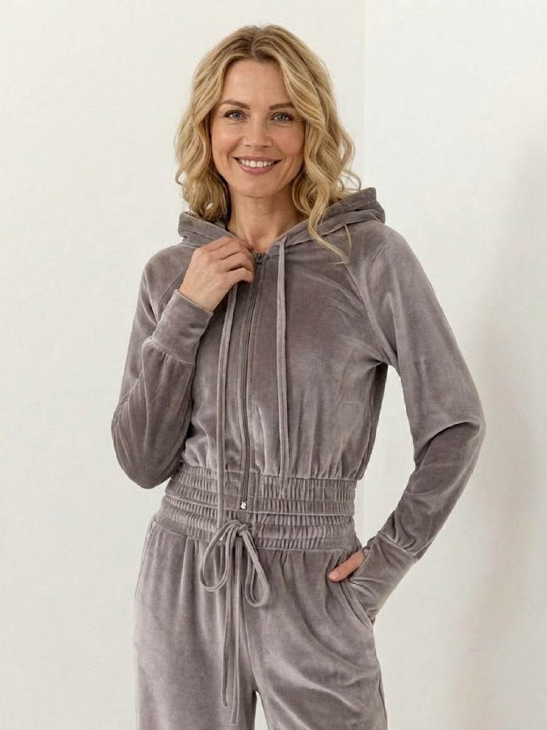 Woman wearing modern cropped velour tracksuit with hoodie and high-waist pants in soft polyester fabric