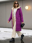 Woman wearing purple sherpa-lined hooded teddy coat with beige pants and black boots walking outdoors in winter