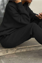 Woman wearing black cotton blend tracksuit with relaxed fit sitting outdoors
