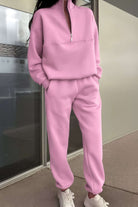 Pink cotton blend tracksuit with zippered high collar and relaxed fit, styled with white sneakers.